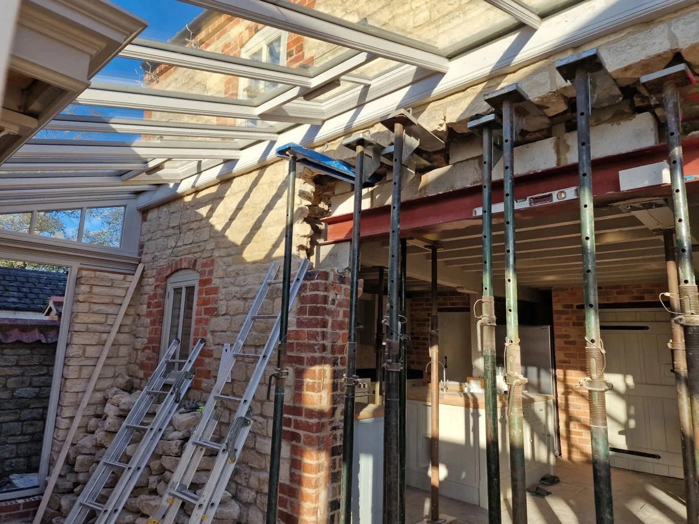 Structural opening in progress on a stone cottage — steel beam installed with acrow props and roof lantern above